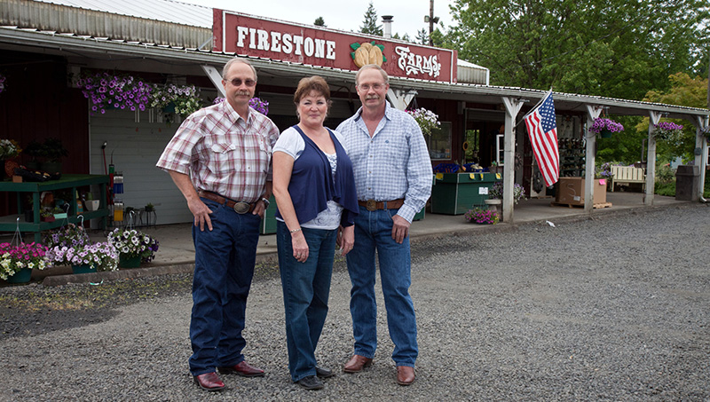 Photo, left to right: Clark Firestone and his wife Joan, and his identical twin brother Mark,at their farm stand in Dayton, Ore.