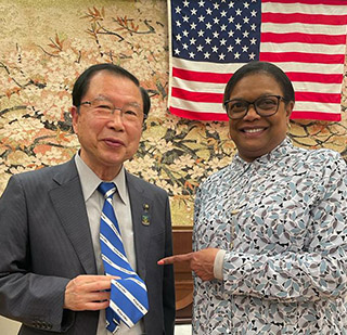 President Karin Edwards, right, points to the Penguin Nation tie that Toshiharu Okuda, mayor of Joyo City, is wearing during a March visit to Joyo, Japan.